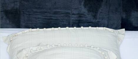 Una cama con ropa de cama blanca y un cabecero oscuro.
