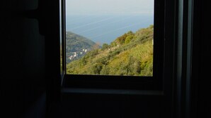 Una ventana con vista a un paisaje montañoso y un cuerpo de agua distante.