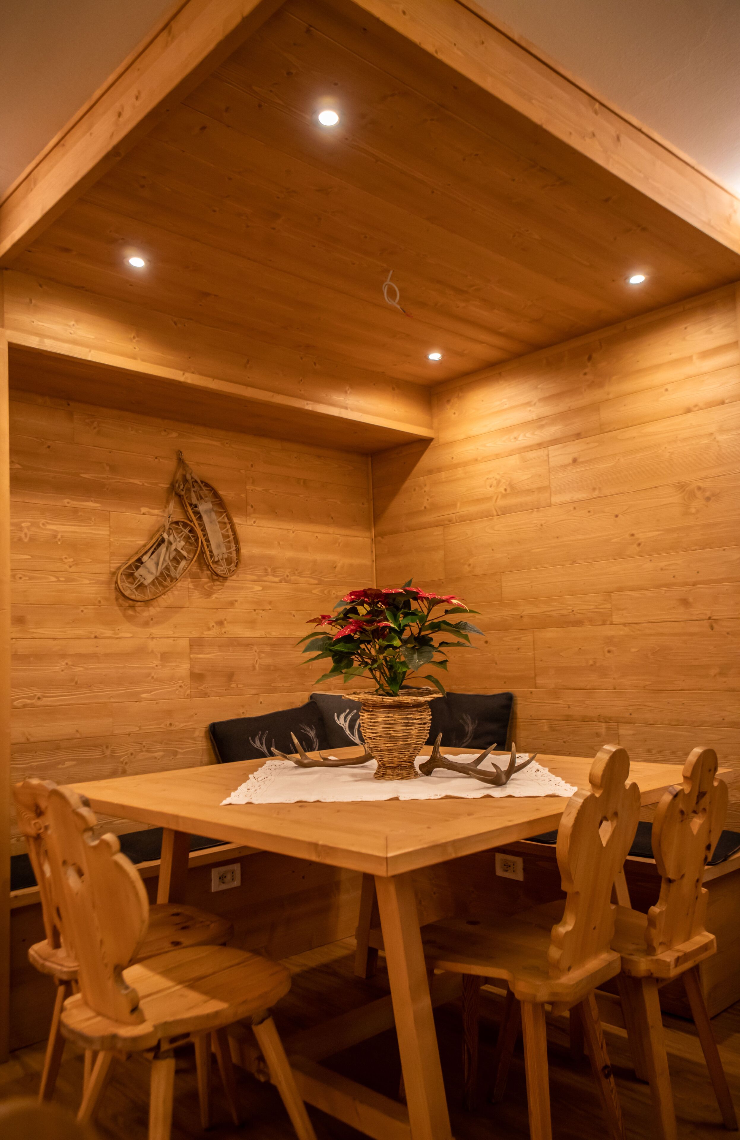 Una sala da pranzo in legno con tavolo, sedie e un vaso di fiori.