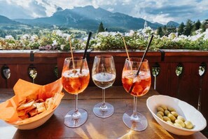 Three glasses of drinks on a table with a scenic mountain view in the background. - Panda  (Cortina d'Ampezzo)