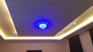 Un techo moderno con una lámpara azul central e iluminación empotrada a lo largo de los bordes.
