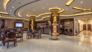 A hotel lobby with a reception desk, seating area, and a television screen. - Rivan Palace Serviced Apartments (Riyadh)