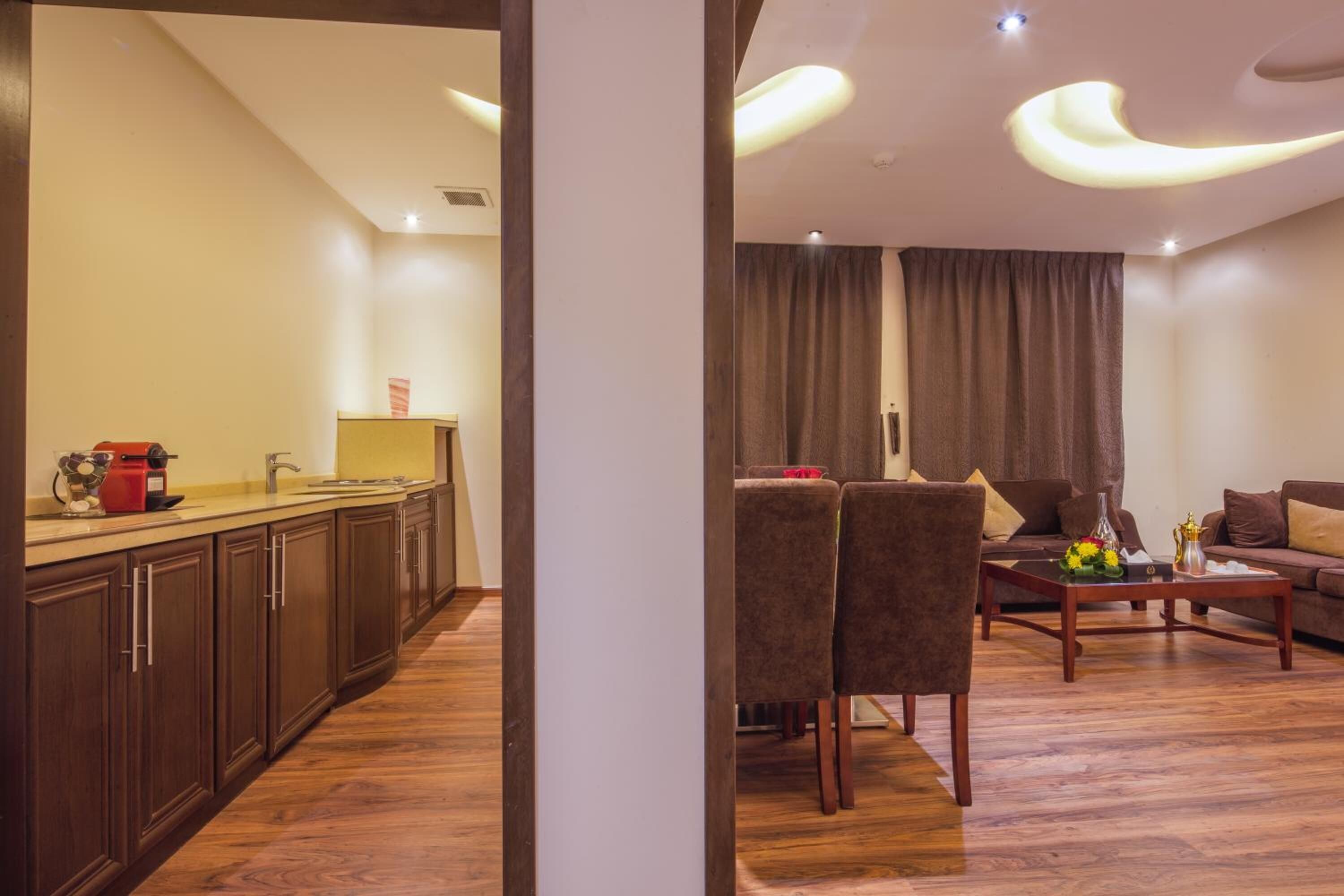 Un moderno espacio de sala con una mesa de comedor, sillas y un sofá. Cuenta con una zona de cocina con armarios y una encimera.