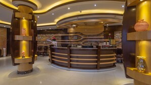 A reception area with a curved wooden desk, a stone wall, and a modern ceiling design. - Rivan Palace Serviced Apartments (Riyadh)