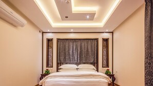 A bedroom with a bed, a ceiling light fixture, and a wall-mounted air conditioner. - Rivan Palace Serviced Apartments (Riyadh)