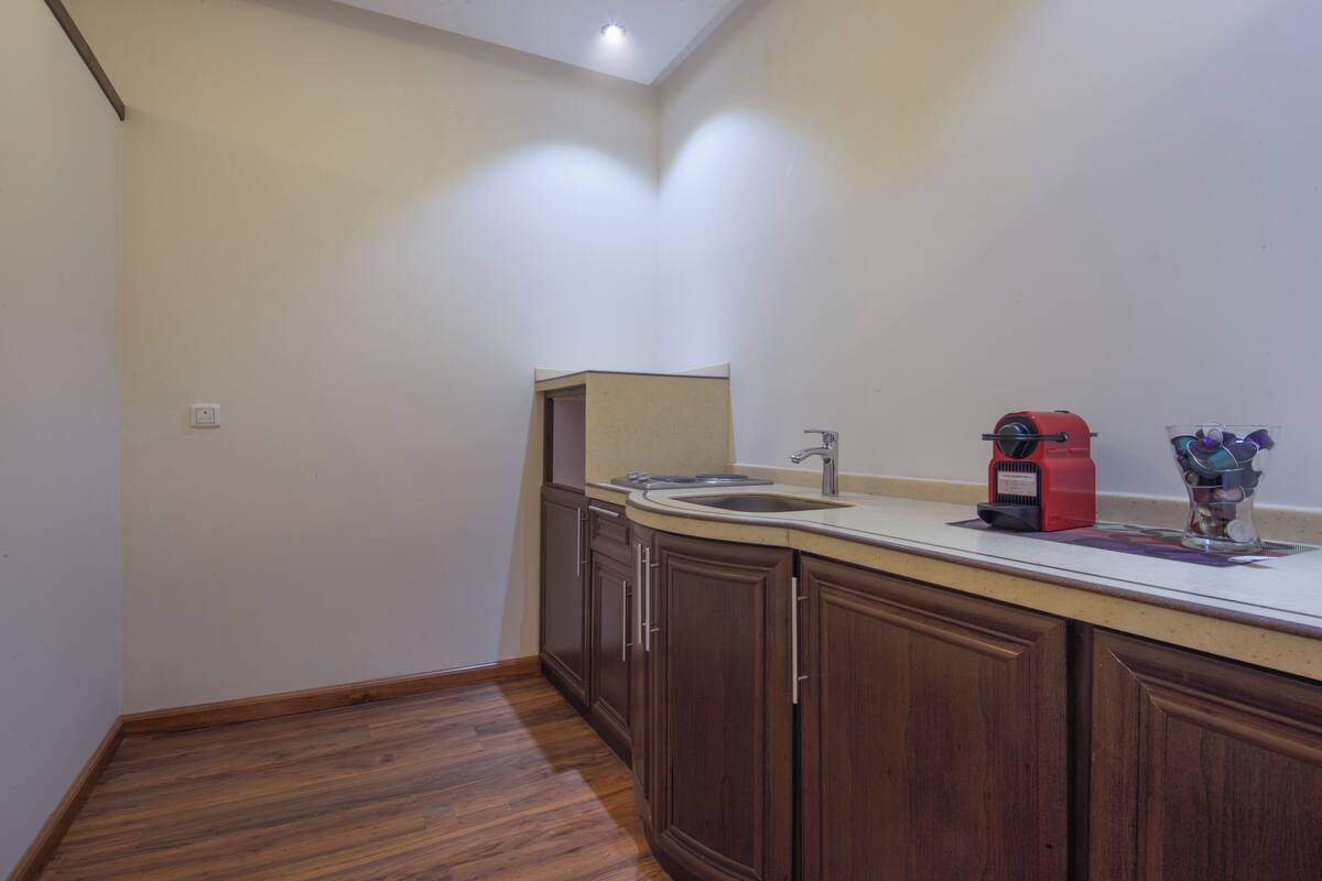 A kitchen with wooden cabinets, a sink, and a coffee maker.