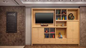 Un salon moderne doté d’un grand téléviseur à écran plat, de meubles en bois et d’une enseigne indiquant « GARANTIE HOME2 ».