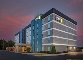 Un moderno edificio de hotel con señalización "HOME 2", varios pisos y un estacionamiento.