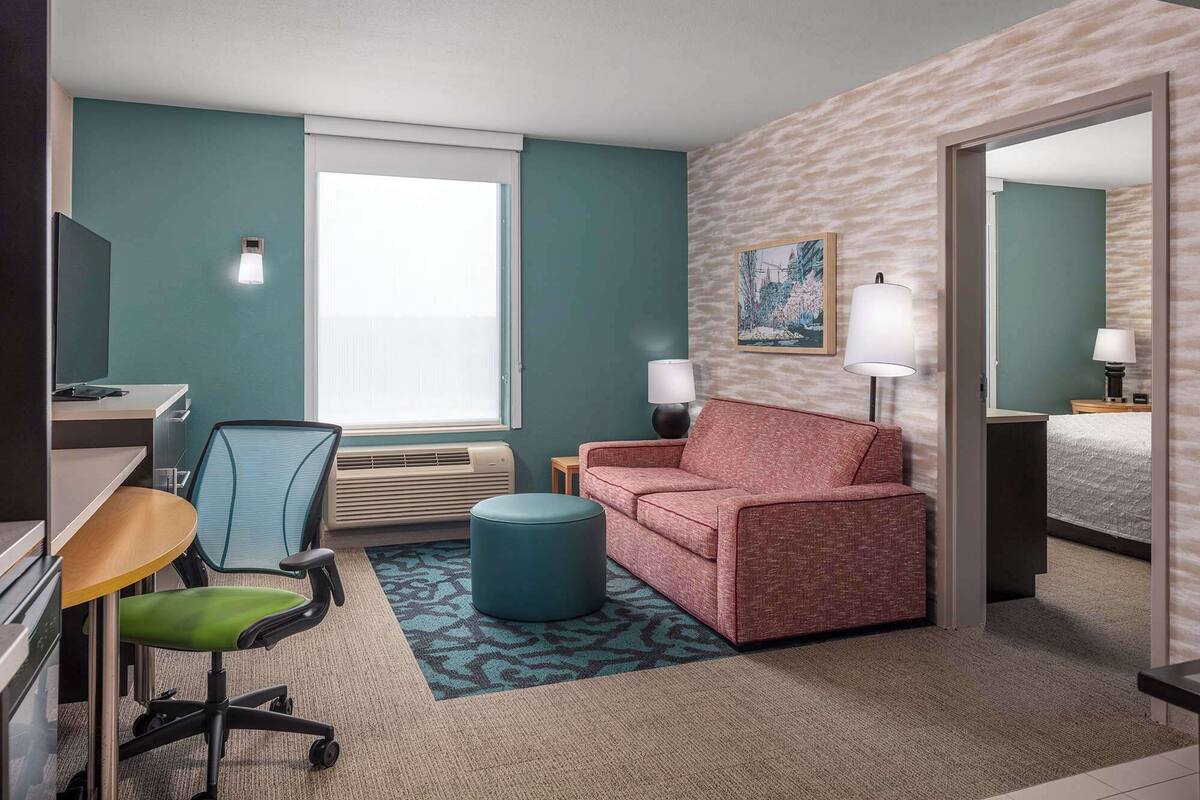 A hotel room with a desk, chair, couch, and a bed.