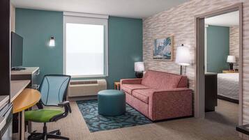 A hotel room with a desk, chair, couch, and a bed.