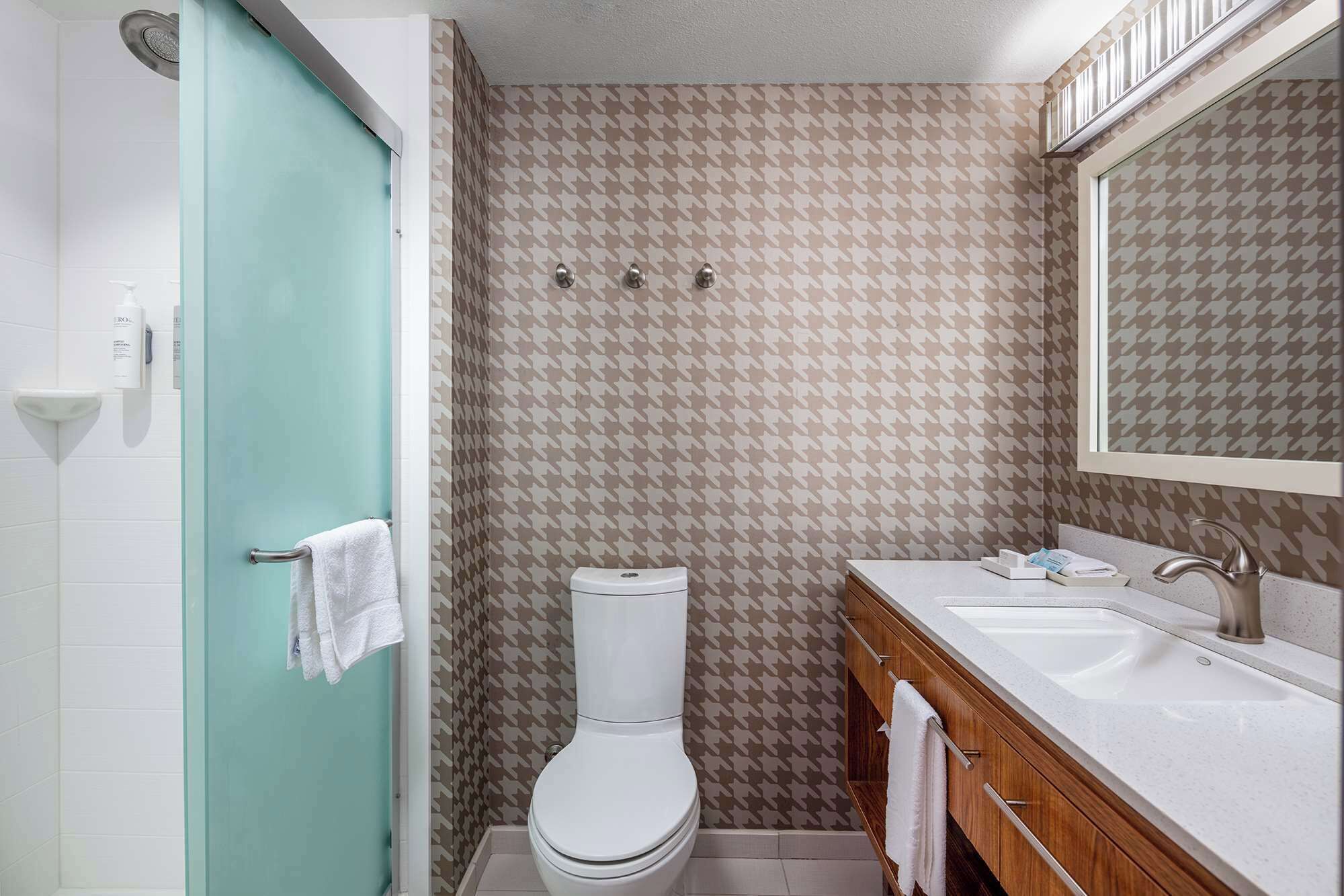 Een badkamer met douche, toilet en wastafel.