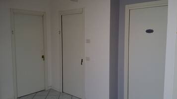 Un pasillo con tres puertas blancas, numeradas 1, 2 y 3, y una pequeña placa en la tercera puerta.