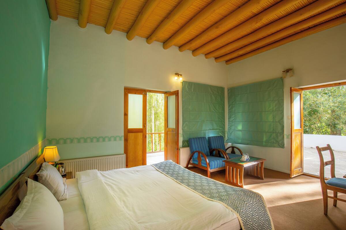 Um quarto com cama, cadeira, mesa e janela.