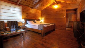 Una cabaña de madera con una cama, dos sillas, una mesa y un televisor.