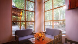 Una habitación con ventanas amplias, muebles de madera y una planta en maceta sobre una mesa.