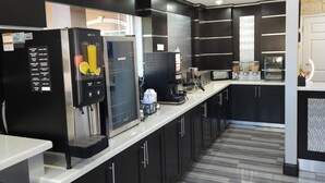 A modern kitchen with black cabinets, stainless steel appliances, and a marble floor.