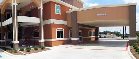 A multi-story building with a covered entrance and a clear sky.
