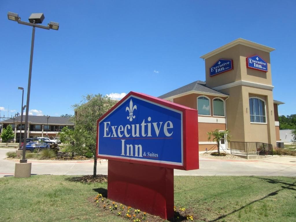 Placa de hotel com o nome 'Executive Inn & Suites' e um edifício com uma placa semelhante.