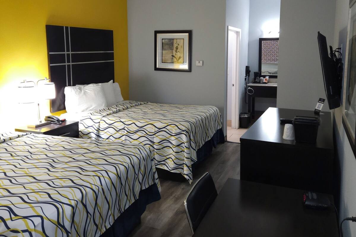 Hotelkamer met een bed, een bureau en een stoel. Er hangt een foto aan de muur en er is een raam.