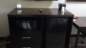 Eine schwarze Unterhaltungseinheit mit einem flachbildfernseher darüber, einer kleinen Fernbedienung und einem gerahmten Bild an der Wand.