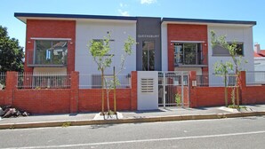 A modern building with a sign reading "QUEENSBURY." It features a brick facade, large windows, and a gated entrance.