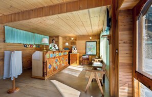 A wooden cabin interior with a reception desk, a map on the wall, and a small dining area.