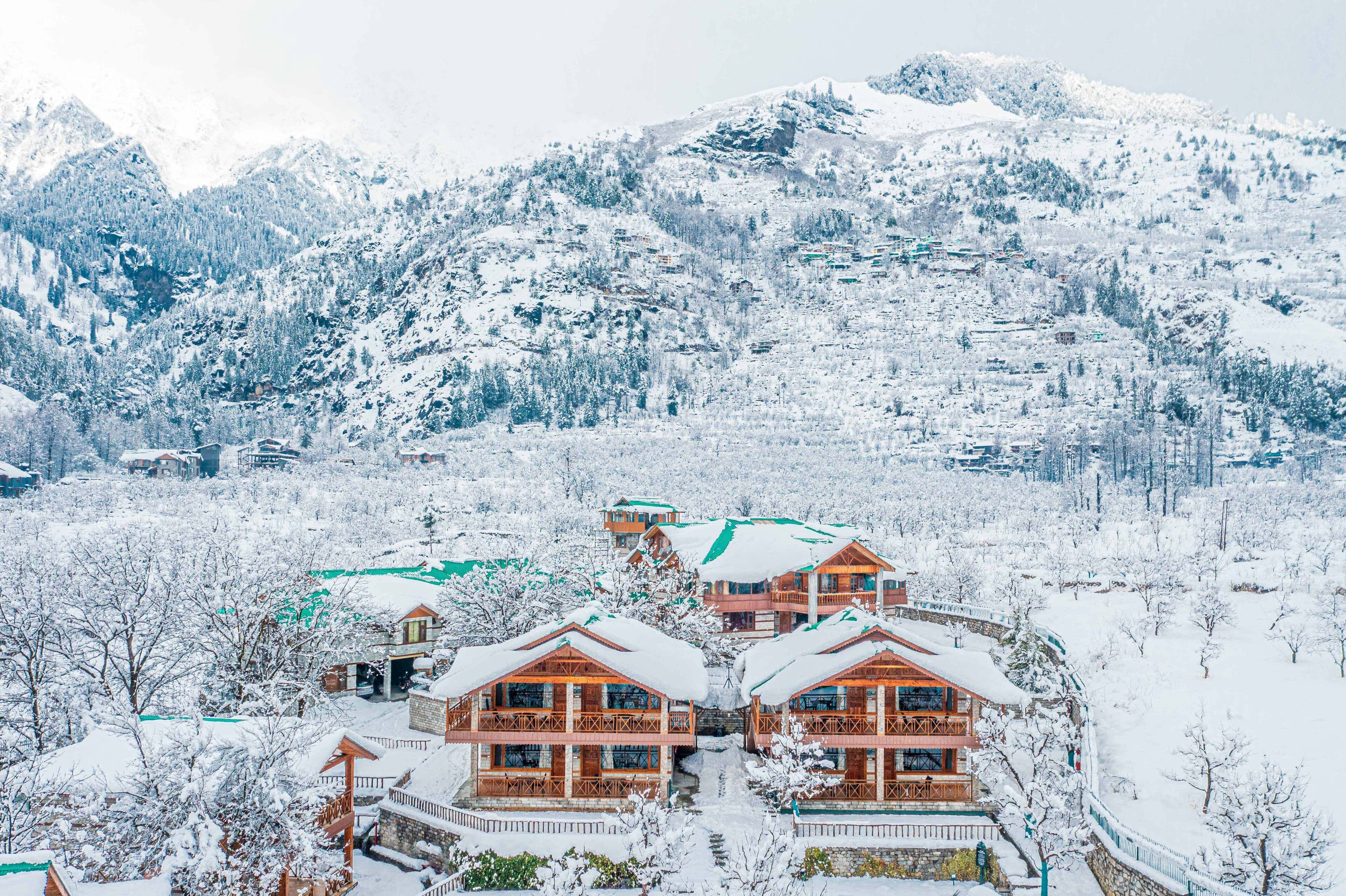 A snow-covered mountain resort with wooden buildings and a ski slope.