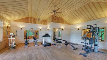 A gym with wooden walls, ceiling fan, and various exercise equipment.