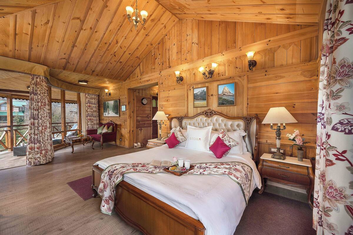 A wooden cabin bedroom with a large bed, wooden walls, and a wooden ceiling.