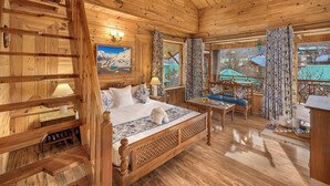 Una habitación de cabaña de madera con una cama, una mesita y vistas a un paisaje montañoso.