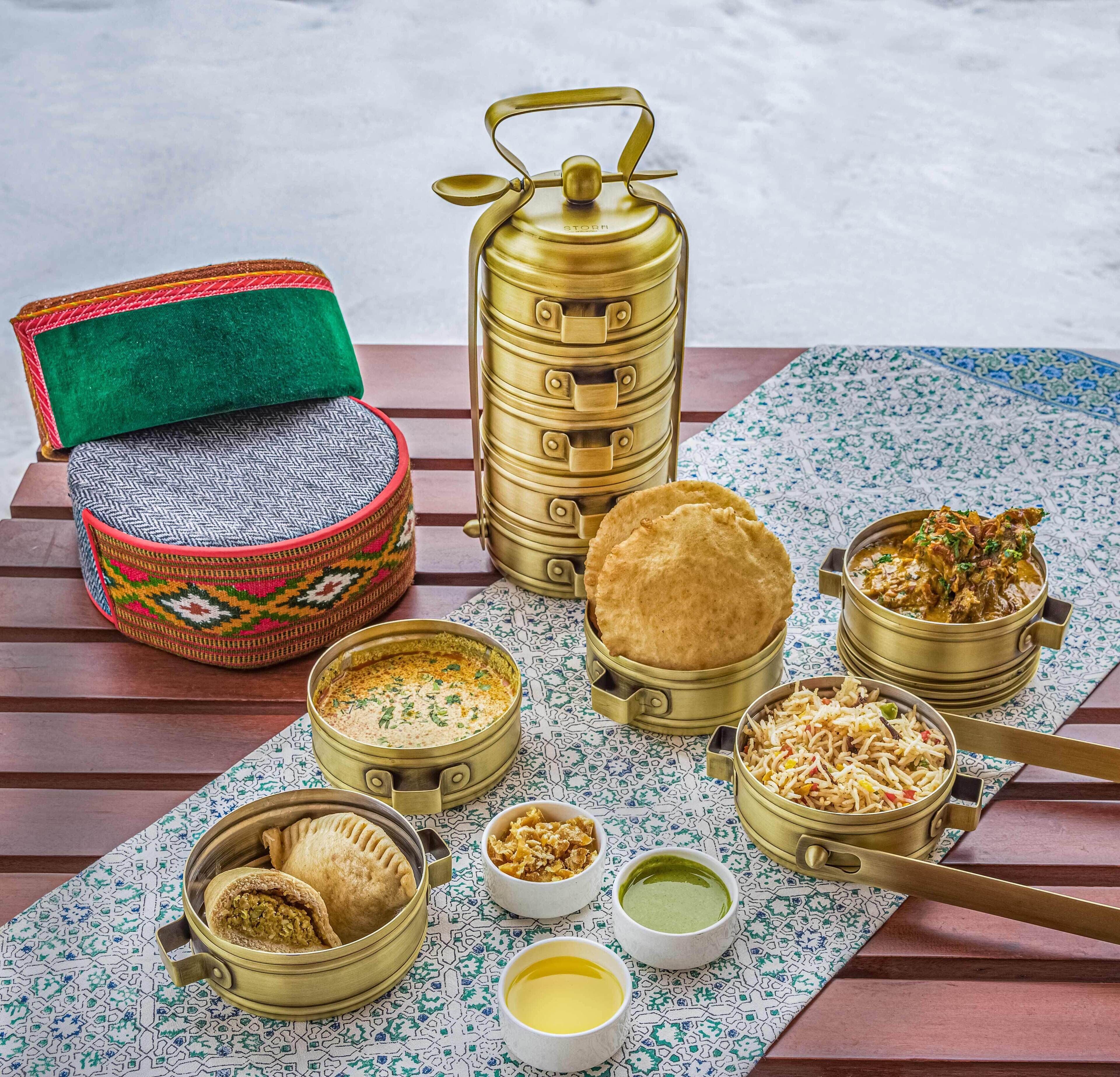 A table with various food items and containers, including a samosa, a samovar, and several bowls of food.