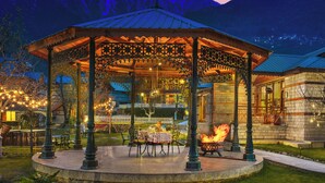 Un pabellón con una chimenea, asientos al aire libre y vistas a montañas al fondo.