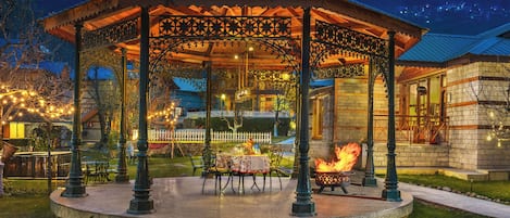 Un pabellón con una chimenea, asientos al aire libre y vistas a montañas al fondo.