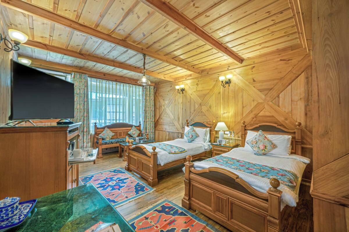 A wooden cabin with two wooden beds, a desk, and a television.