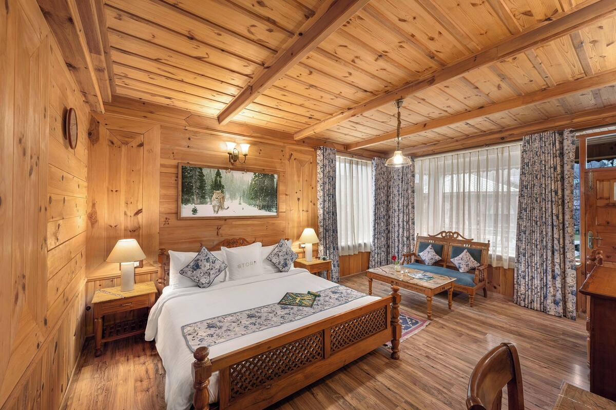A wooden cabin-style room with a bed, a desk, and a sofa.
