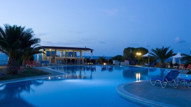 A swimming pool with lounge chairs and a building in the background. - Akti Corali (Malevizi)