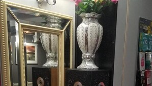Et spejl med gylden ramme, en hvid vase med lyserøde blomster, og en vase med lilla og lyserøde blomster.
