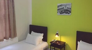 A room with a bed, a nightstand with a lamp, and a wall-mounted picture. - City View Hotel Roman Road (London)