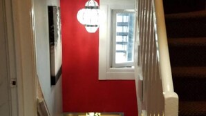 En trappe med rød væg og hvid gelænder, der fører op til en etage.