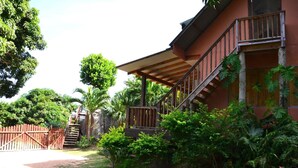 A two-story building with a wooden staircase and a covered porch. - Kaz Ladouceur (La Digue)