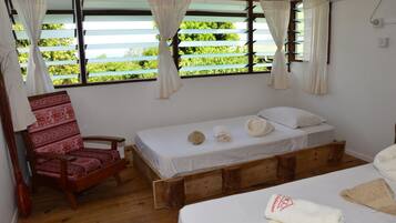 A room with a wooden bed, a patterned chair, and a window with curtains.