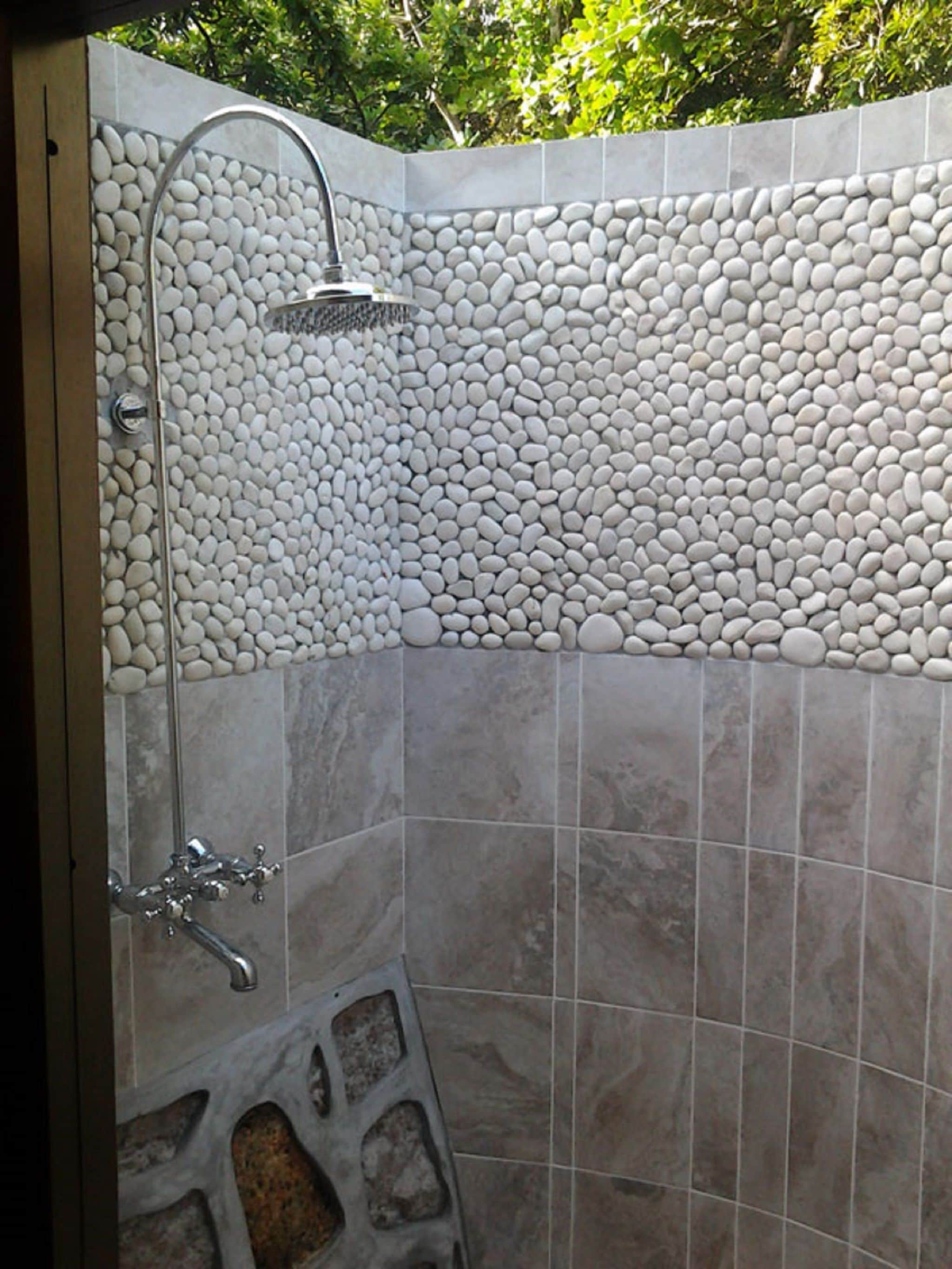 Un área de ducha con pared de piedra y suelo de baldosas.