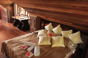 Una habitación de madera con una cama, almohadas y una computadora portátil sobre una mesa.