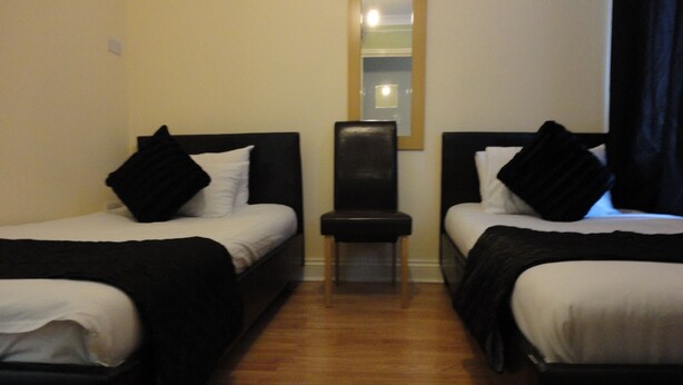 Quarto de hotel com duas camas, uma cadeira e um espelho na parede.