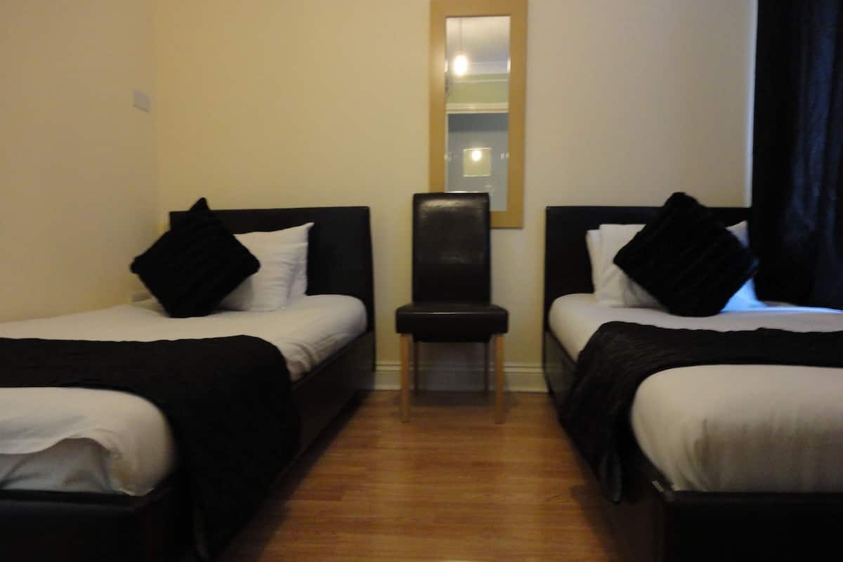 Una habitación de hotel con dos camas, una silla y un espejo en la pared.