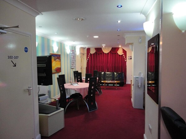 A hotel room with a dining area featuring a round table and chairs, a sofa, and a red carpet. - City View Hotel Roman Road Market (London)