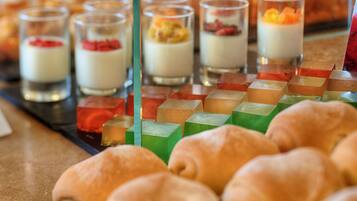 Un présentoir de desserts proposant une variété de douceurs, notamment de petits verrines de desserts en couches et des cubes de gelée de couleurs vives.