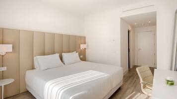 Ein Hotelzimmer mit einem großen Bett, Nachttischen, einem Sessel und einem Schreibtisch.