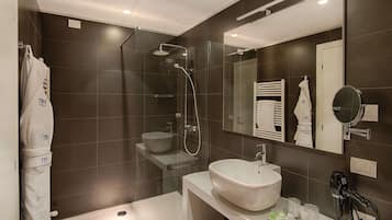 A modern bathroom with a glass-enclosed shower, a white sink, and a vanity with toiletries.