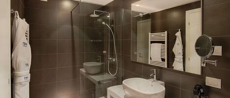 A modern bathroom with a glass-enclosed shower, a white sink, and a vanity with toiletries.